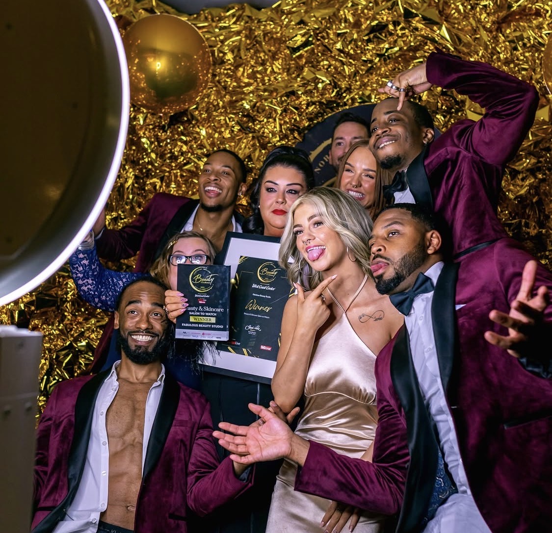 Group celebrating with gold sequin backdrop at a selfie booth
